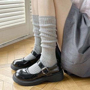 Dettaglio di calze a costine grigio chiaro abbinate a scarpe Mary Jane nere lucide
