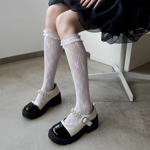 Detail of white lace hosiery with floral mesh and bows paired with Mary Jane platform shoes