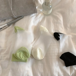 Close-up of three pairs of ultra-thin sheer glass silk socks in green, beige and black