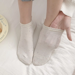 Close-up of white low-cut socks with colorful dots and breathable mesh texture
