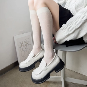 Détail de chaussettes hautes blanches jacquard cœur et mocassins à plateforme pour femmes