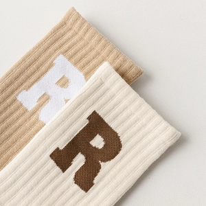 Makroaufnahme der Rippstruktur und R-Buchstaben-Jacquard auf Baumwoll-Yogasocken