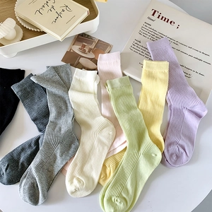 Détail de chaussettes en coton côtelé coloré aux tons Morandi sur table marbre