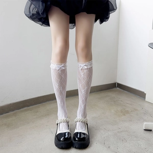 Close-up of white lace knee-high socks with delicate floral hollow patterns and sweet bows