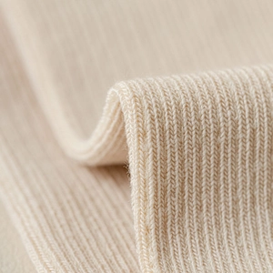 Macro shot of cream ribbed knit fabric texture showing high elasticity and soft fiber