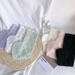 Detailed view of lace hollow knit socks in various pastel colors on a woven mat