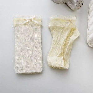 Detail of cream white lace socks featuring ribbon bows and delicate mesh texture