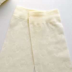 Détail des chaussettes blanches montantes avec motifs jacquard en forme de petit cœur