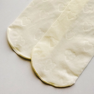Détail macro de chaussettes hautes crème avec motif de cœurs en relief et maille douce