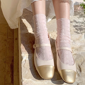 Detail of floral lace socks paired with beige Mary Jane shoes featuring a gold toe cap