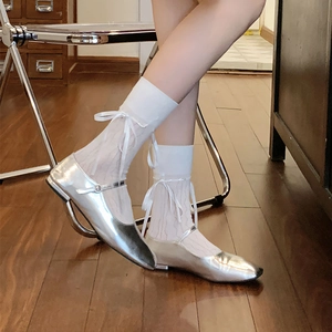 Detail of white mesh ballet socks with silk ribbons and silver Mary Jane flat shoes