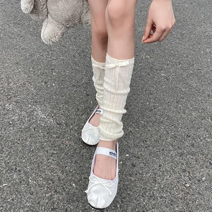 Detail of white balletcore leg warmers with ribbon bows and heart pearl accents