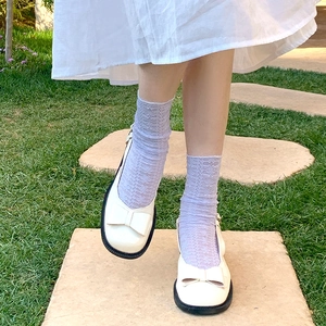 Detail of light purple lace socks paired with Mary Jane shoes on a lush green lawn