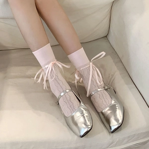 Close-up of pink lace socks with satin bows paired with silver Mary Jane shoes