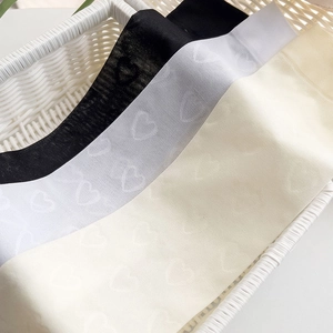 Détail de chaussettes hautes transparentes avec motifs de cœurs en blanc et beige