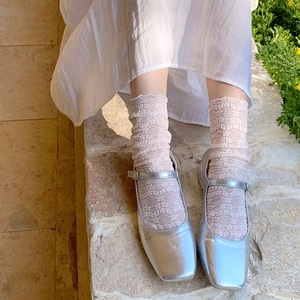 Silver square toe Mary Jane flats paired with delicate beige lace socks in a lifestyle view