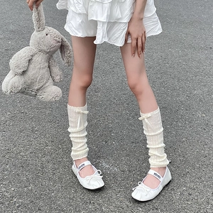 Close-up of white ribbed leg warmers with delicate bows and ballet flat shoes