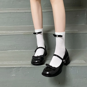 Close-up of white JK style socks with pearl bow details and black Mary Jane shoes