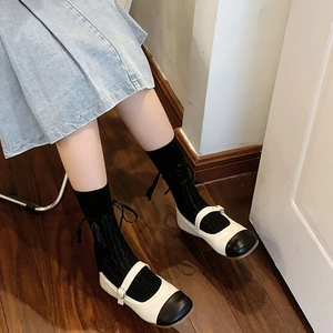 Close-up of Mary Jane shoes in beige and black with adjustable buckle strap detail