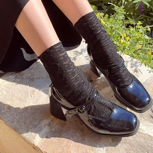 Women black patent leather square toe Mary Jane heels with lace socks in outdoor setting