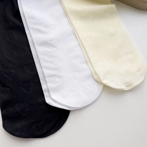 Détail de chaussettes hautes blanches et beige avec motifs jacquard cœur 3D délicats