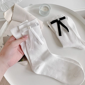 Détail de chaussettes blanches en maille côtelée avec nœuds et pendentifs cœurs