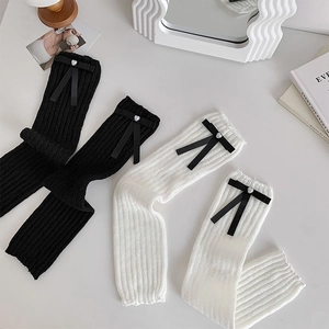 Detail view of balletcore leg warmers with ribbon bows and heart bead accents