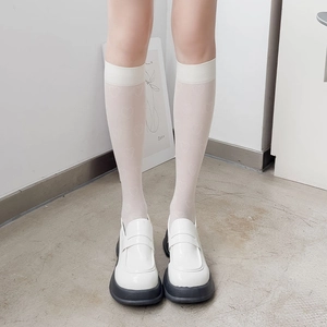 Détail de chaussettes hautes blanches à motifs cœurs et mocassins à semelles compensées