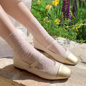 Close-up of sheer floral lace mid-calf socks paired with beige Mary Jane flat shoes