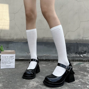 Detail of black patent leather Mary Jane shoes paired with white diamond pattern socks