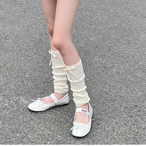 Detailed view of white ballet flats with matching ribbed knit leg warmers and bows