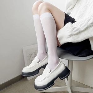 Détail de chaussettes montantes blanches à motif cœur avec des mocassins à semelles