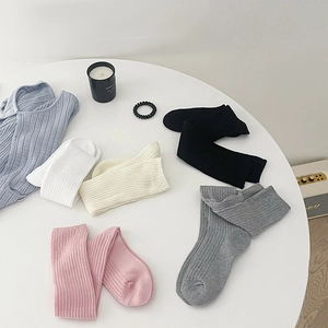 Dettaglio di calze in cotone a coste in rosa, grigio, bianco e nero disposte in piano