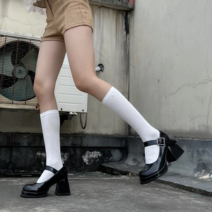Detail of black patent leather Mary Jane shoes with thick soles and silver buckles