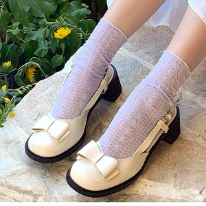 Cream Mary Jane shoes with bow and lace socks shown in an outdoor garden setting