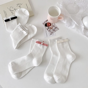 Detail of white knit socks with silk heart pearl bows in black pink and cream