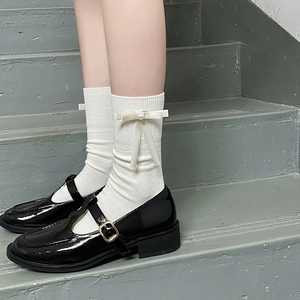 Détail de chaussettes blanches à côtes avec nœuds et perles avec chaussures Mary Jane