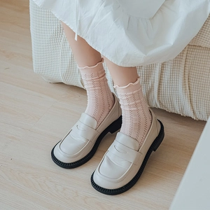 Detail of pink eyelet ruffle socks with lace trim paired with beige leather platform loafers