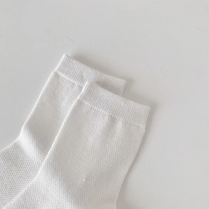 Detail of white mesh knit socks featuring ribbed cuffs and breathable texture in ballet style
