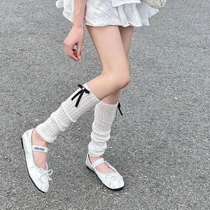 Detail of white ribbed leg warmers with black satin bows and pearls for ballet style