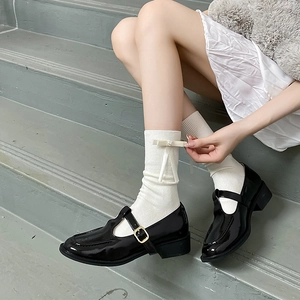 Détail de chaussettes blanches à nœuds et chaussures Mary Jane noires vernies
