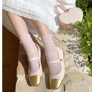 Detail of beige Mary Jane shoes with gold toe cap and pink floral lace mesh socks