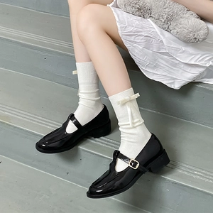 Gros plan de chaussures Mary Jane en cuir verni noir avec chaussettes blanches à nœud
