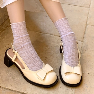 Detail of cream Mary Jane heels with bow and lace socks on stone floor