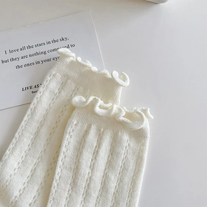 Macro view of white pointelle knit socks with elegant ruffled edges and textures