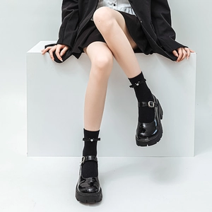Detail of black patent leather platform Mary Janes with bow heart-embellished socks