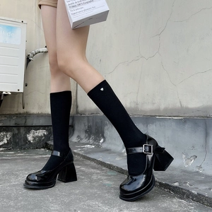 Detail of black knee-high socks featuring small silver heart charms and platform shoes