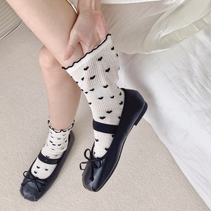 Detail of white mid-calf socks with black hearts and black Mary Jane shoes