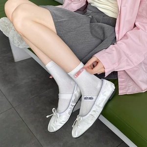 Detail of white ballet flats with bows and mesh socks featuring pink ribbon accents