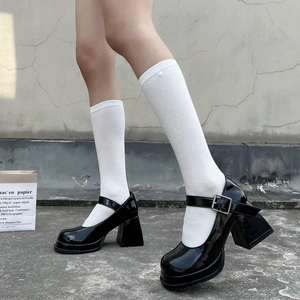 Detail of black platform Mary Jane shoes with white mesh knee-high socks on a model